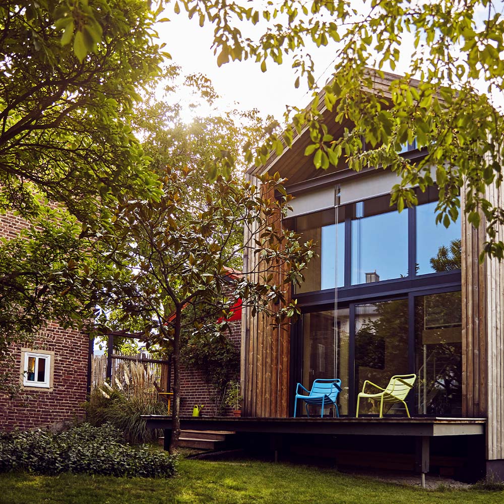 A beautiful garden suite with a wooden deck and tall glass windows sits next to the property’s main house. 