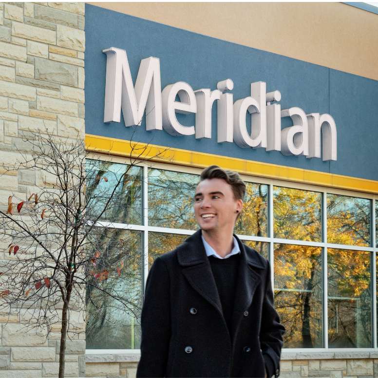 Meridian employee standing outside underneath the Meridian sign