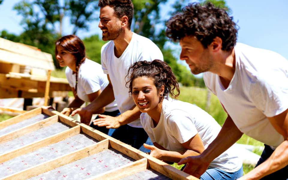 2 men and 2 women lifting a board
