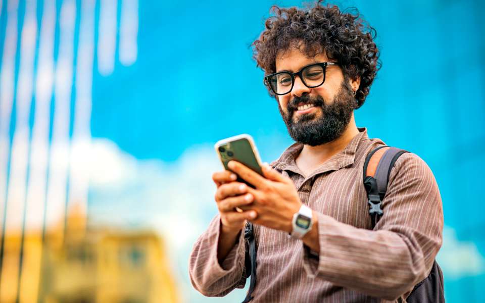 A man wearing a back pack stops to look at his mobile phone