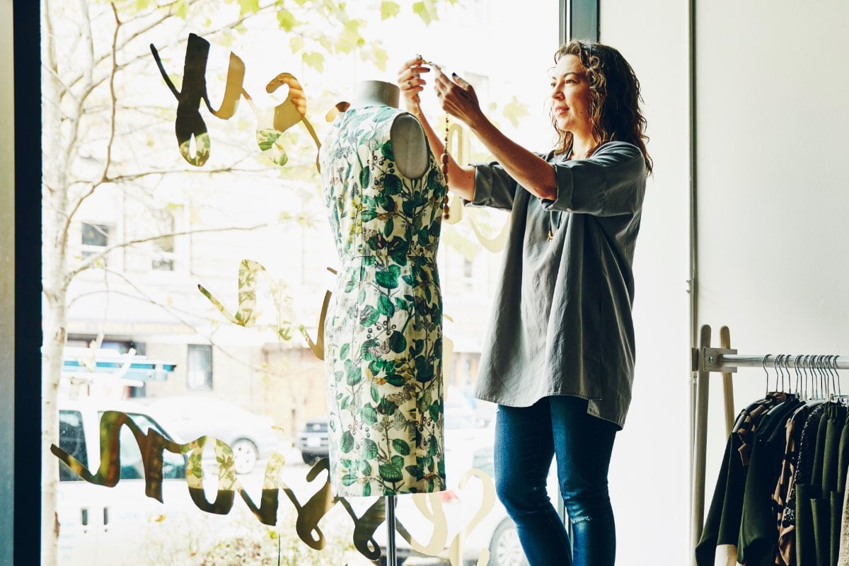 woman small business owner dressing a mannequin