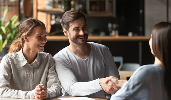 couple shaking hands with financial advisor in a cafe