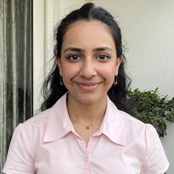 2025 recipient, Anahat Chhatwal, stands smiling on a plant-covered balcony. 
