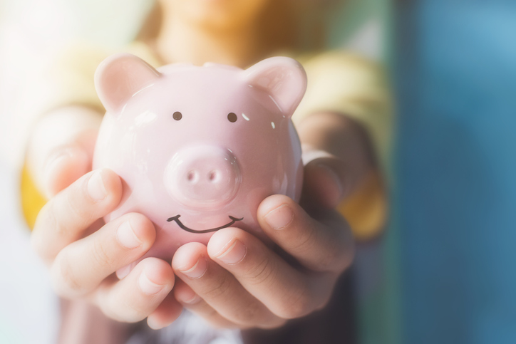 Small hands holding out a piggy bank