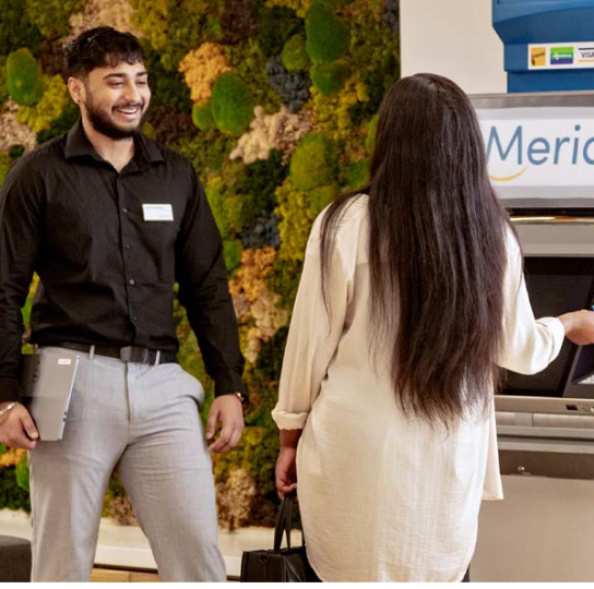 A Meridian branch employee assists a Member at the ATM