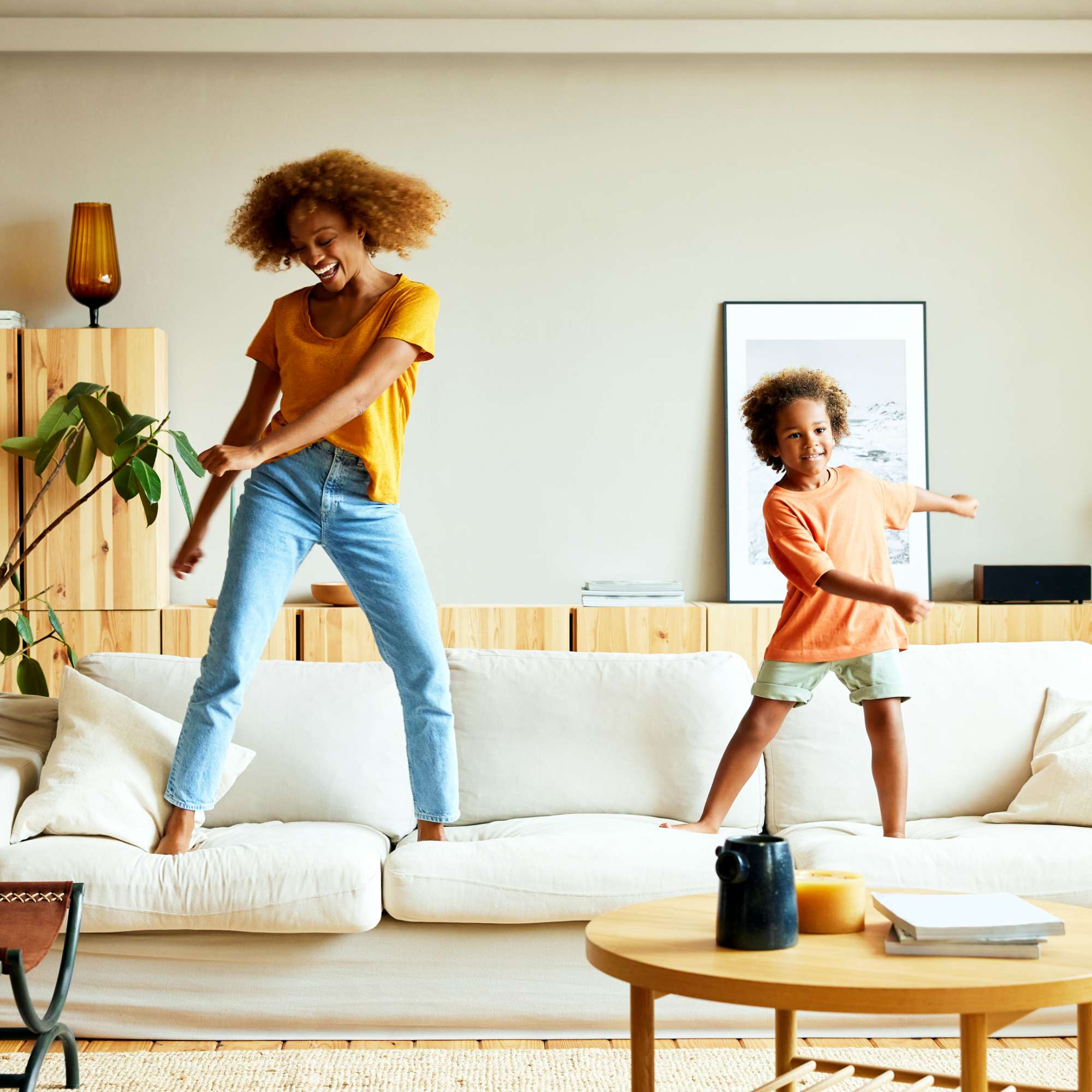 Happy mother and son dancing on a sofa at home