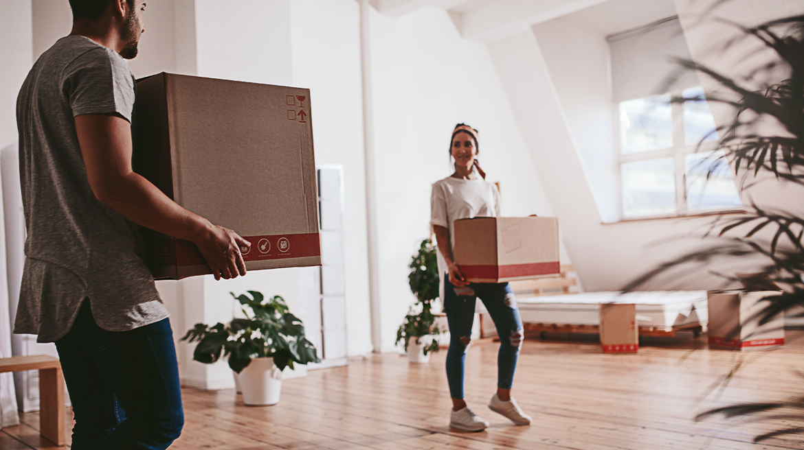 A couple carrying boxes in their living room