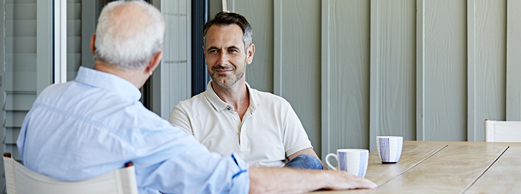 Mature-man-with-father-spending-leisure-time-on-patio-750@280.jpg A man and his father having coffee and talking