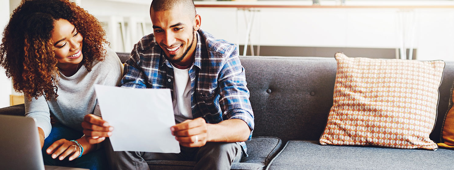 Young couple at home, using laptop to learn more about pre-authorized payments.