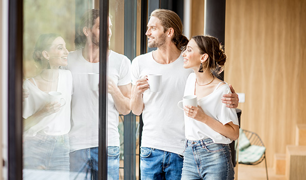 couple looking out into their backyard with their arms around each other and holding coffee mugs