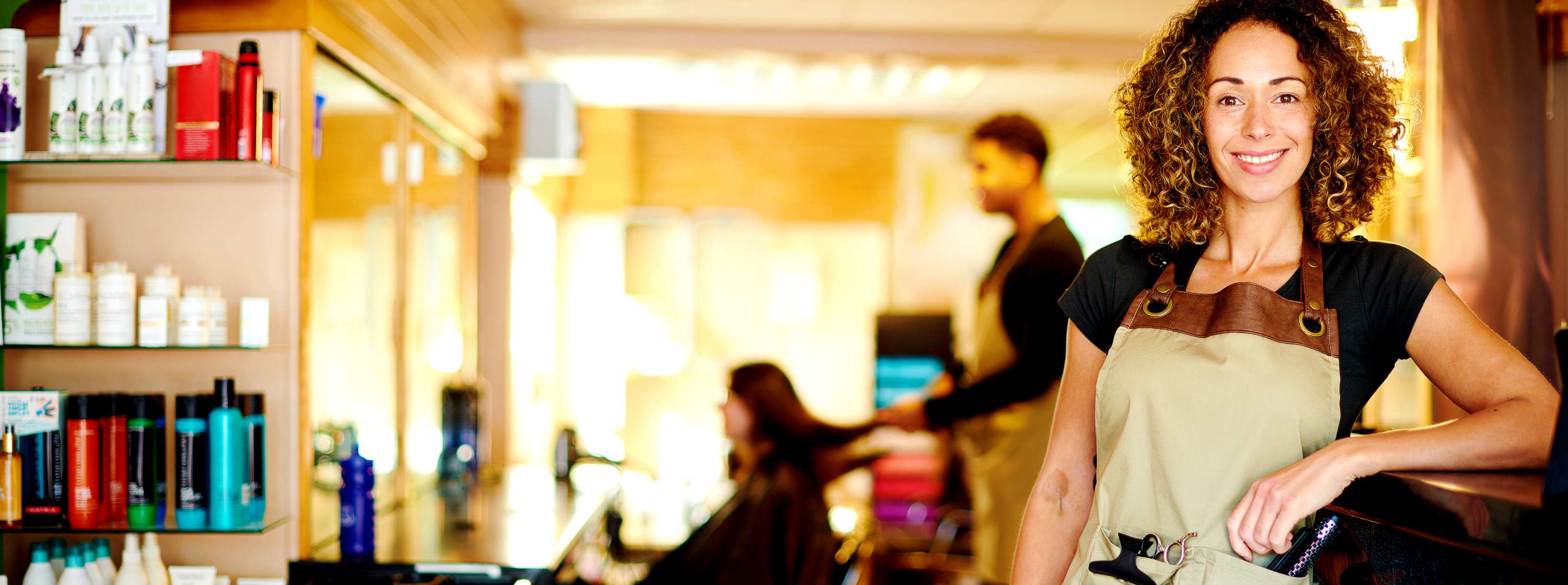 Women standing in a hair salon with a barber cutting a women's hair in the background