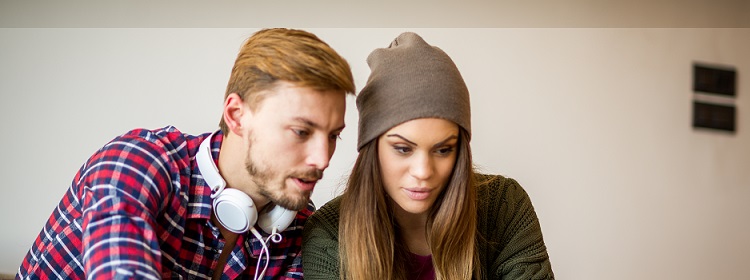 a young man and woman looking at a laptop