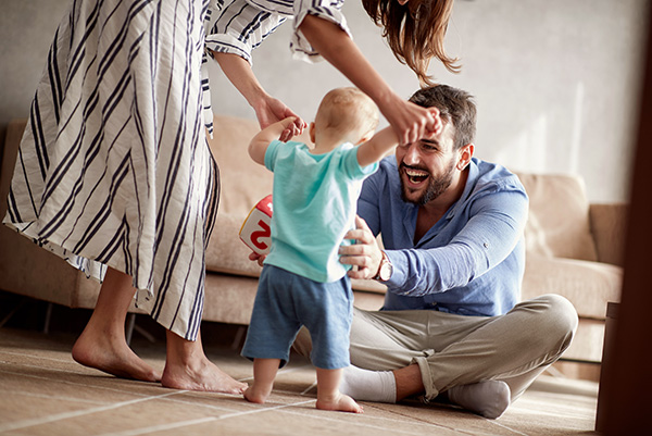 parents helping their young son learn to walk
