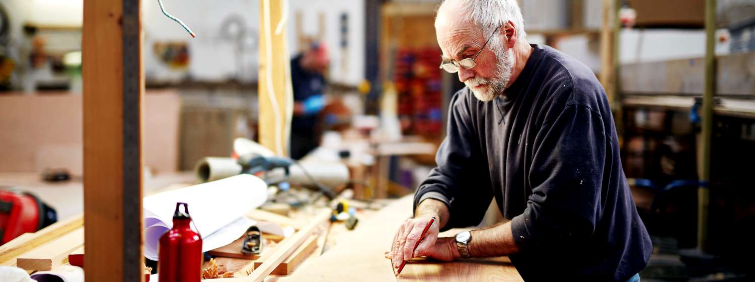 Older man with white hair and glasses working in his garage