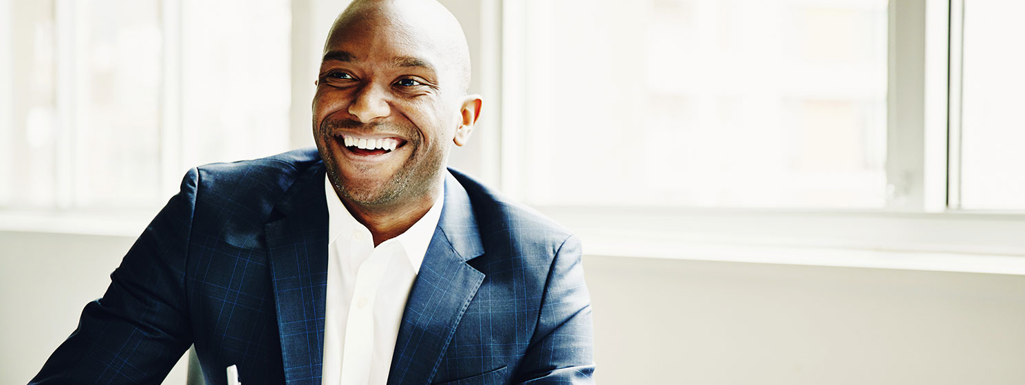 Smiling black man wearing a suit in a bright office. 