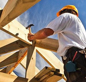 construction worker hammering wood to build a roof