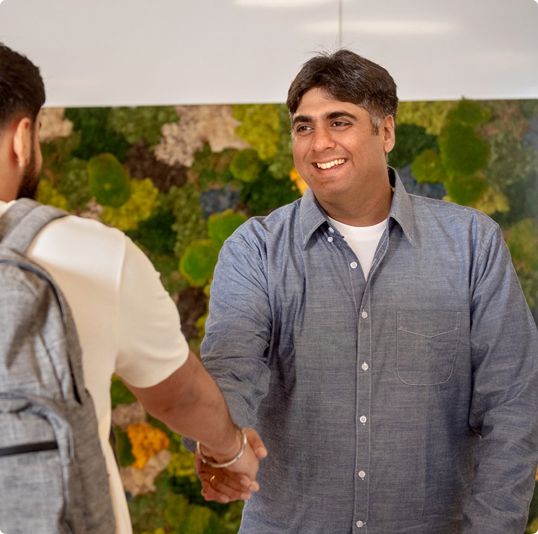 A male Meridian employee with brown skin smiles and greets a Member at our Bramalea City Centre branch.