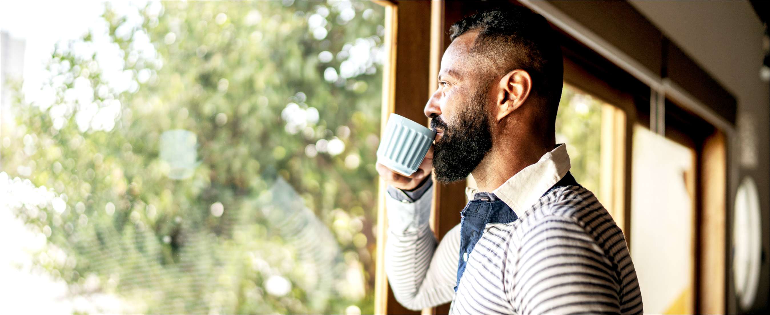 A mature dark-skinned man drinking tea and contemplating at home