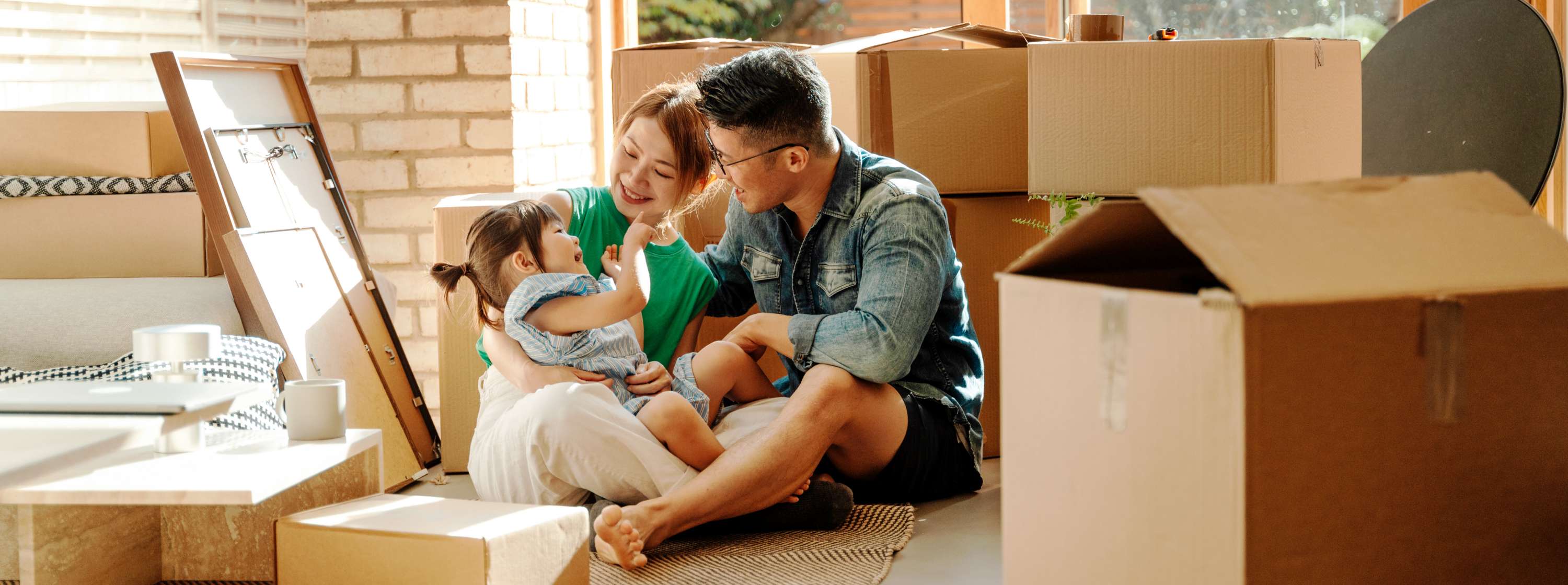 Young family sits among moving boxes in their new home.