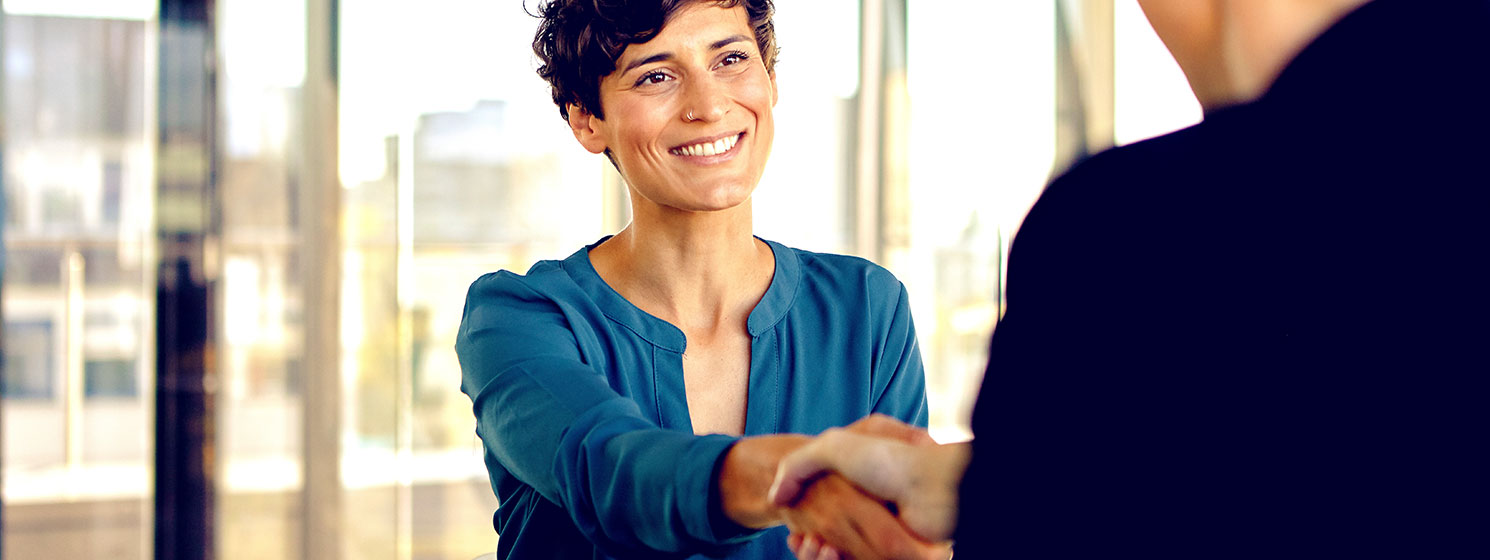 Young women smiling shaking hands with her advisor after signing a mortgage