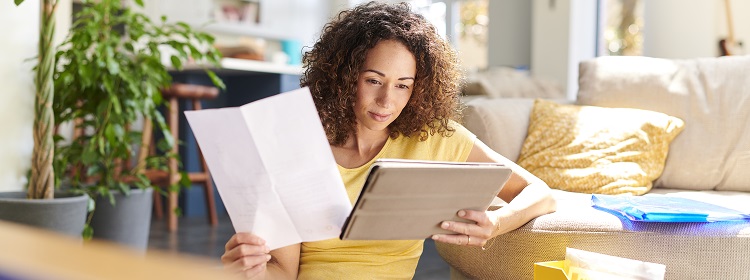 Women staring at her tablet while holding a piece of paper