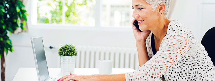 Woman on the phone, while working at laptop