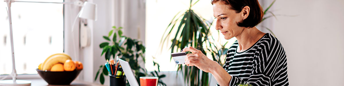 woman holding credit card while on laptop