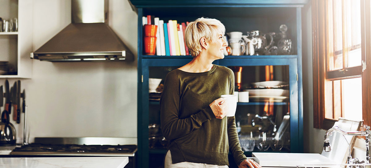 A woman in her kitchen drinks coffee 