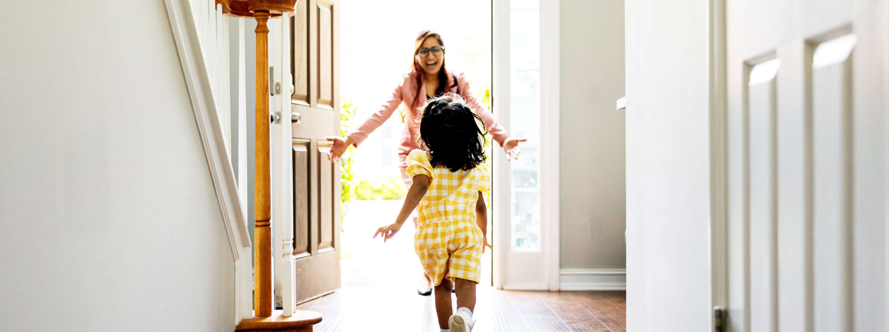 Little girl running to the front door into her mother's outstretched arms