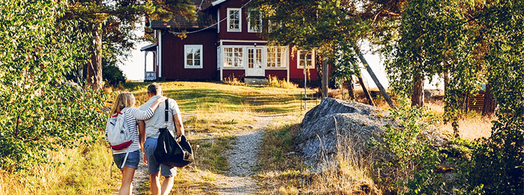 Middle-aged couple walking on pathway towards a cottage