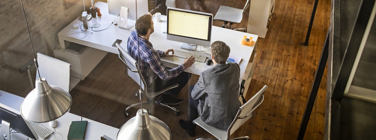 Aerial view of two people working in a modern office, sitting at a computer