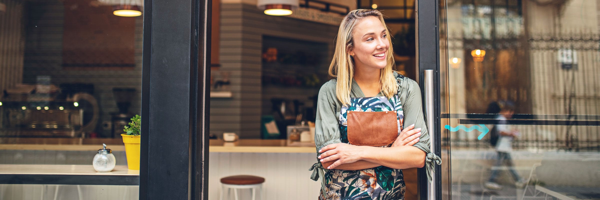 Smiling woman in an apron standing outside her business