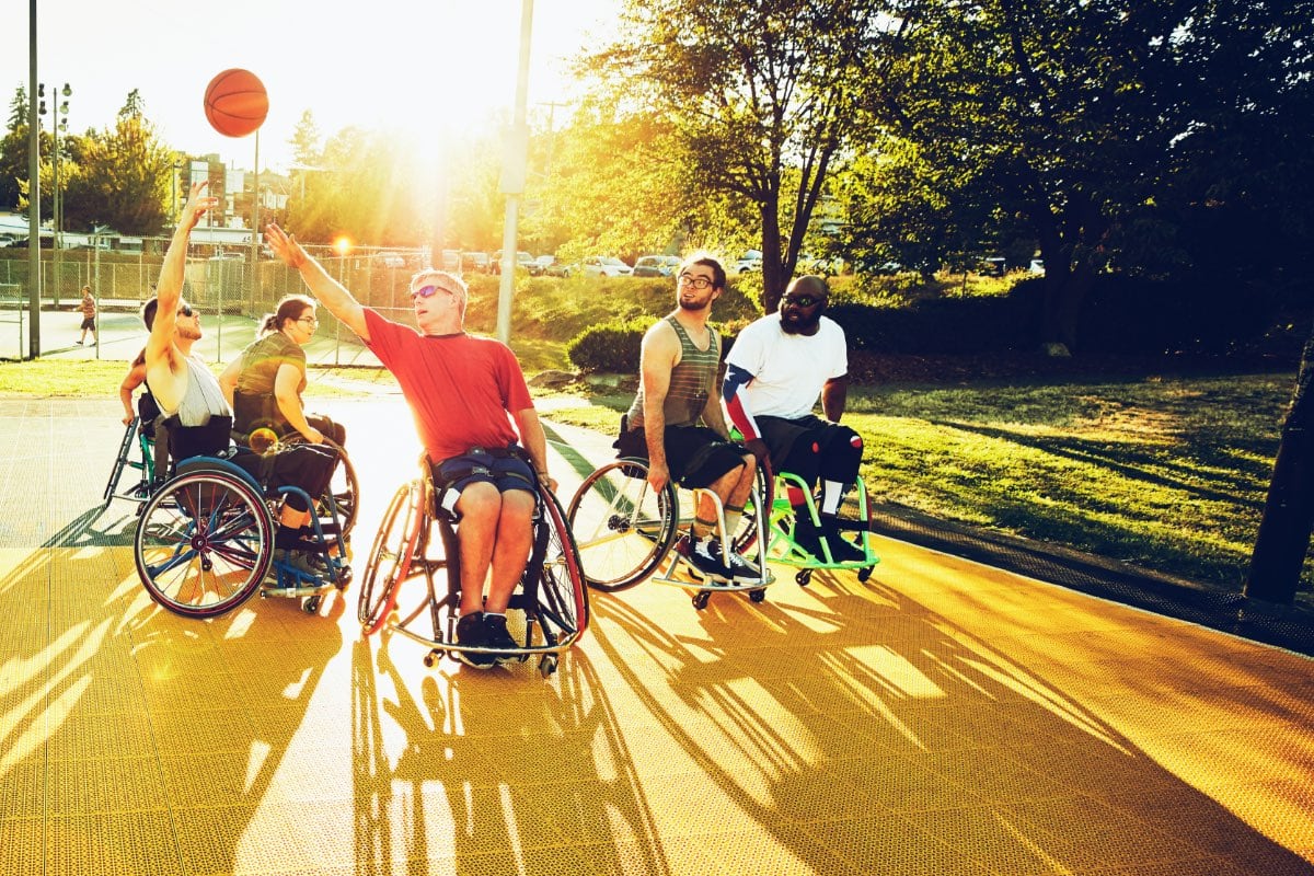 Friends playing wheelchair basketball outdoors