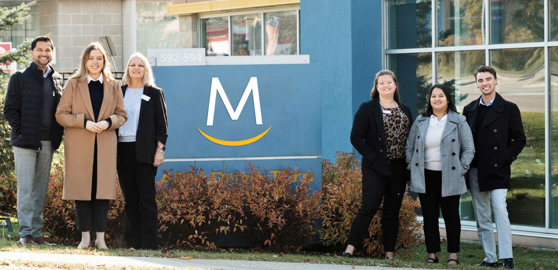 Meridian employees standing beside Meridian logo sign outdoors