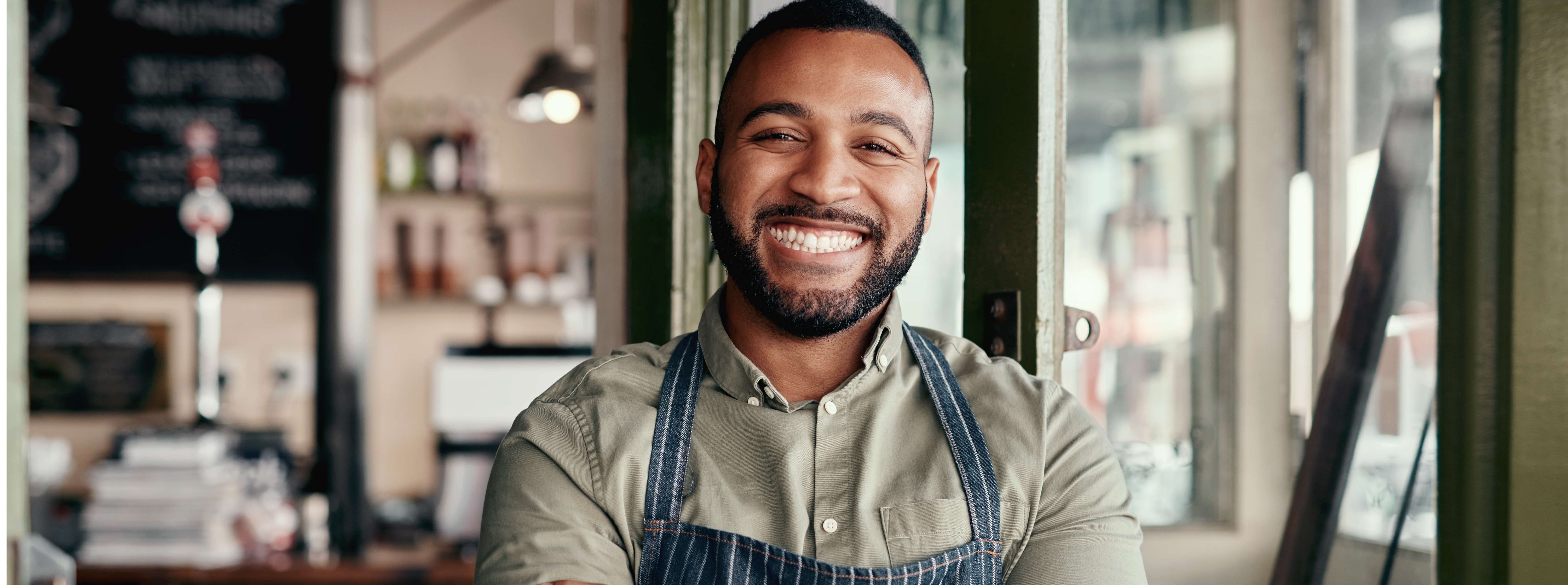 Smiling black man wearing an apron in his restaurant