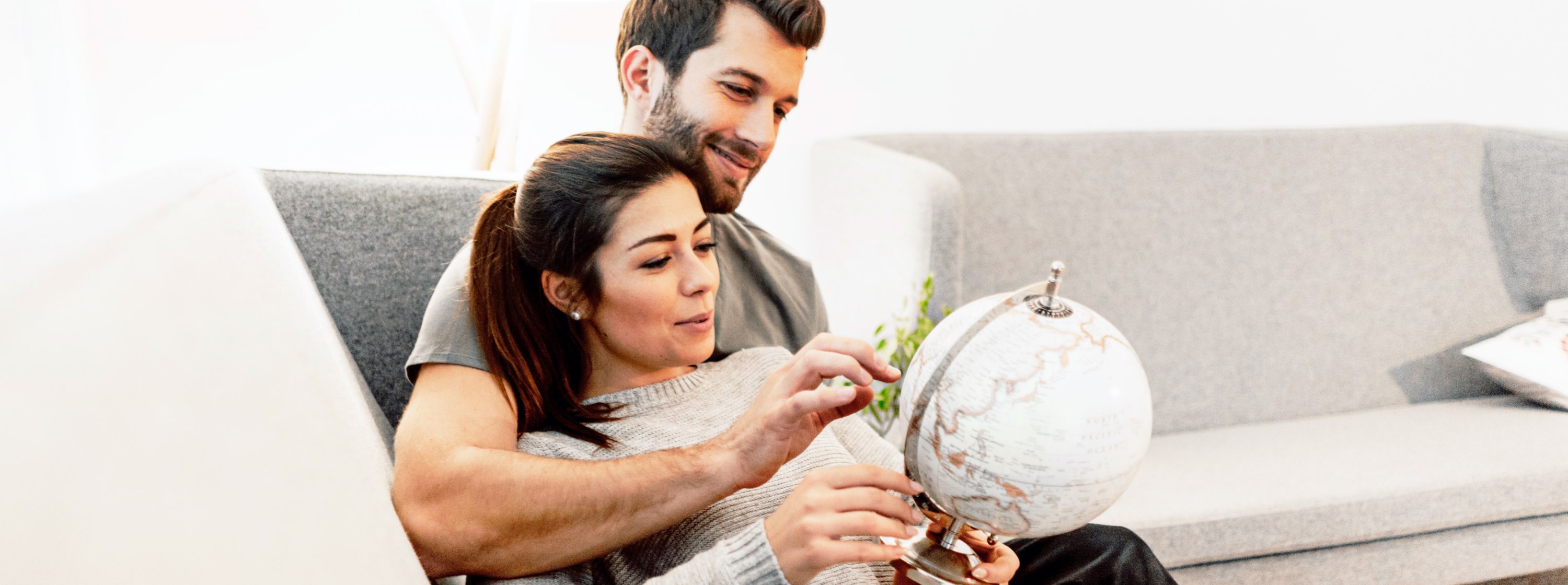 happy couple holding a globe deciding where to travel next