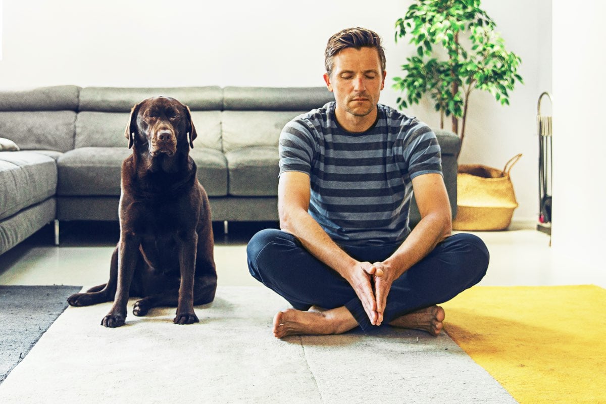 Man meditating with his dog beside him