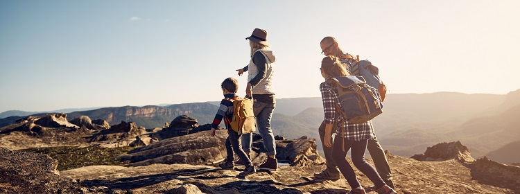 A family is hiking in bright, sun-lit mountains