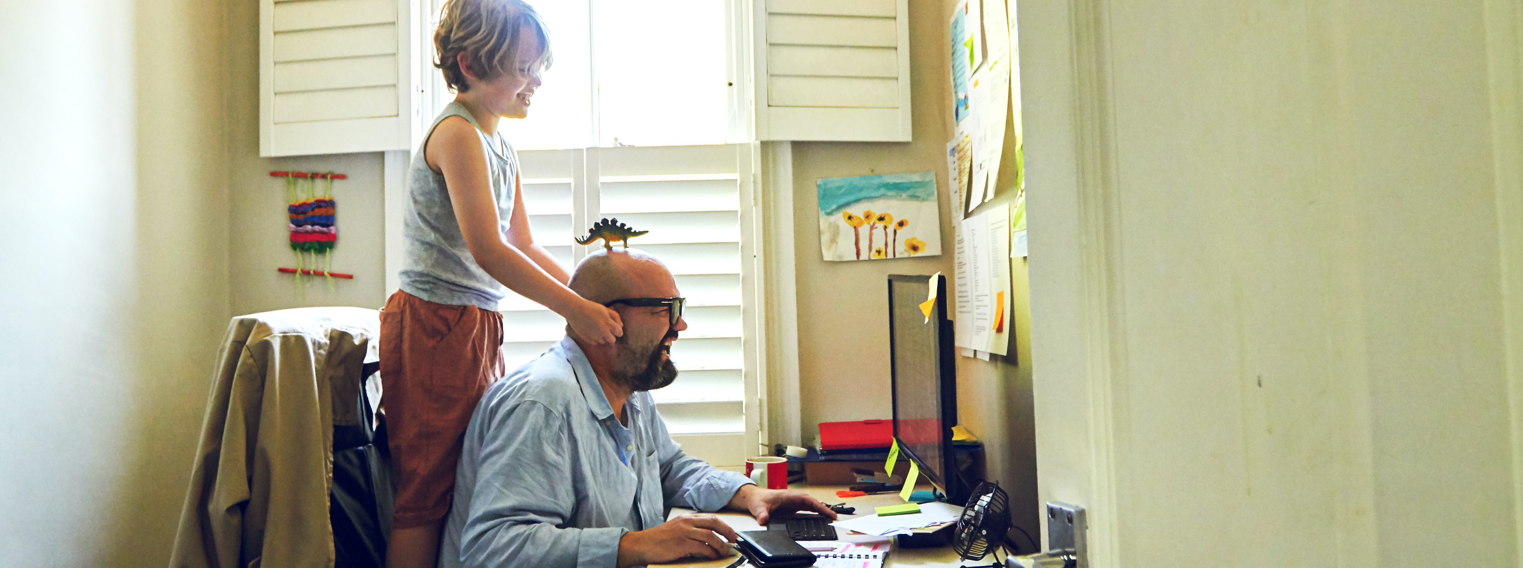 Father trying to work from home while son is distracting him.