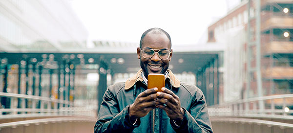 A man smiles while using his phone to make trades