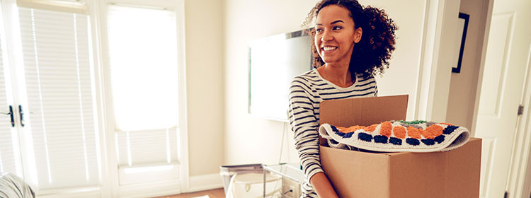 A woman carries boxes into her new home