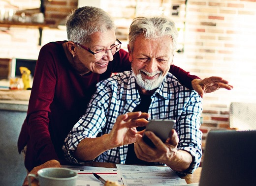 older man and woman holding a mobile phone and smiling