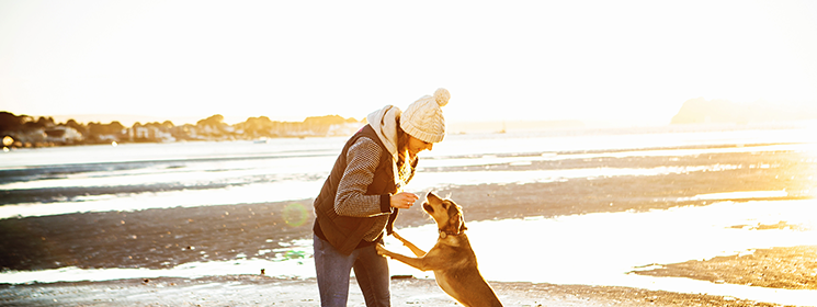 woman playing with her dog at the beach