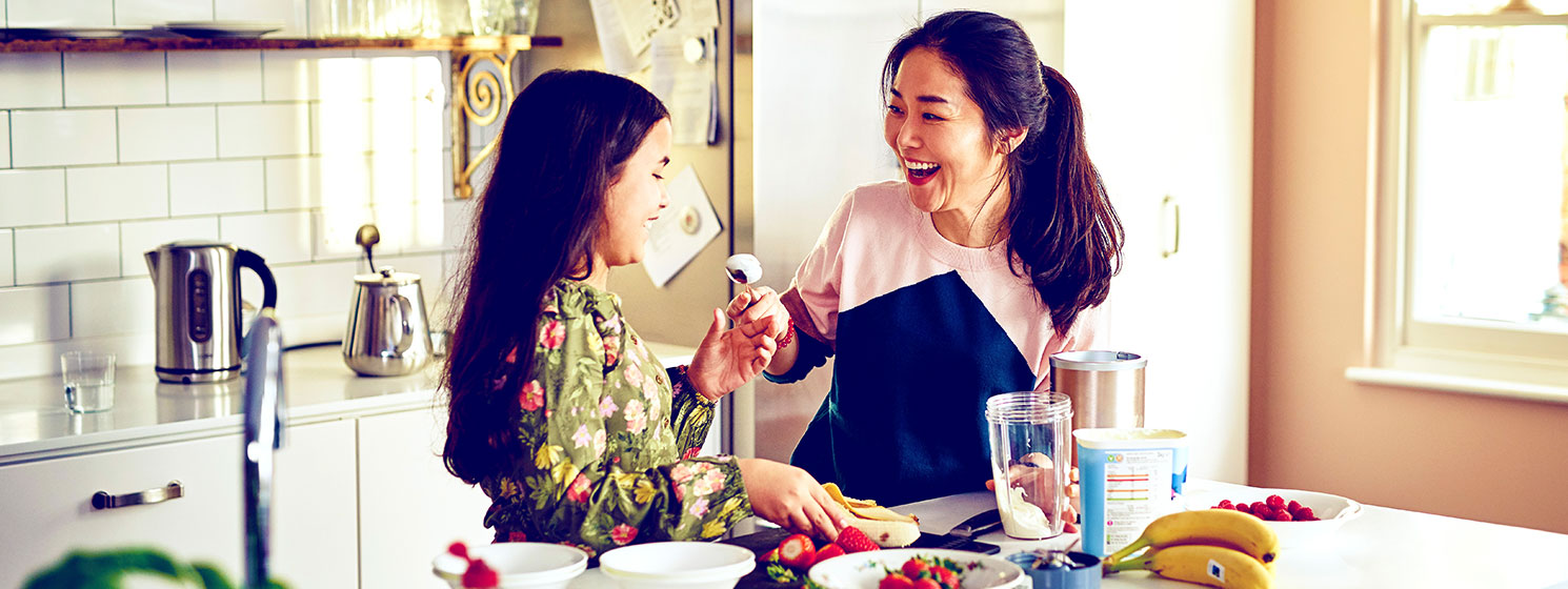 Mother and daughter laughing while preparing food in a kitchen