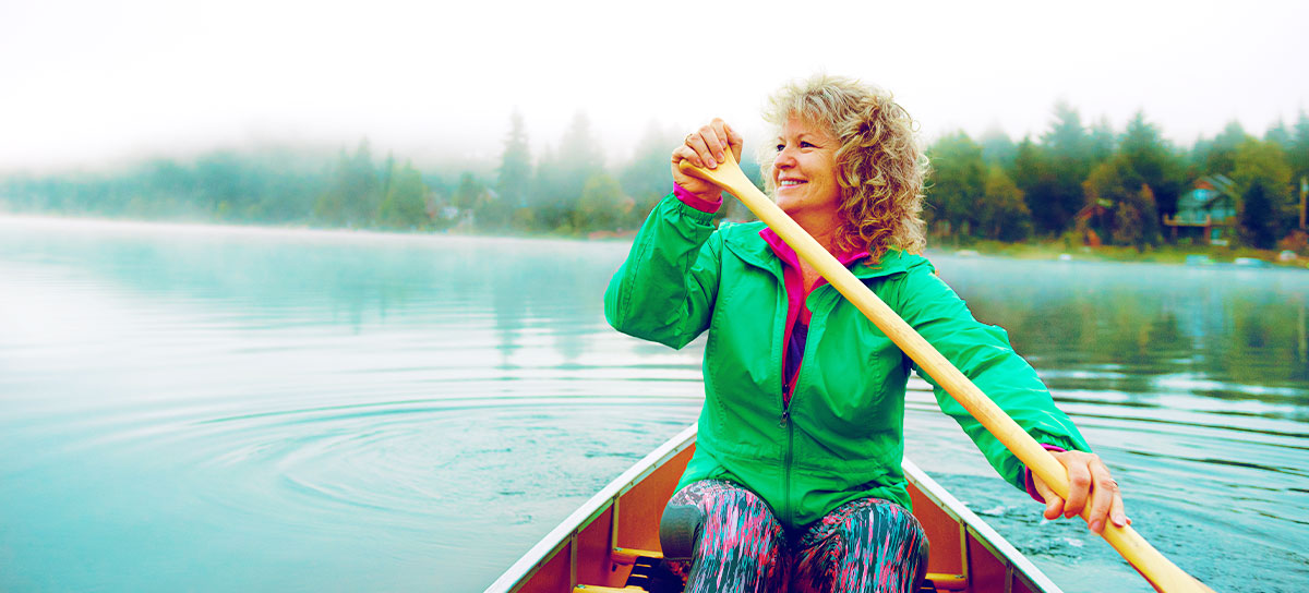 middle aged woman canoeing on a calm lake