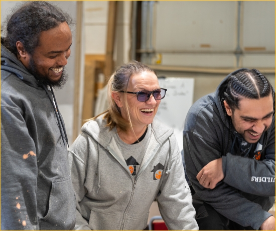 Three people smiling and laughing, wearing Community Builder apparel. 