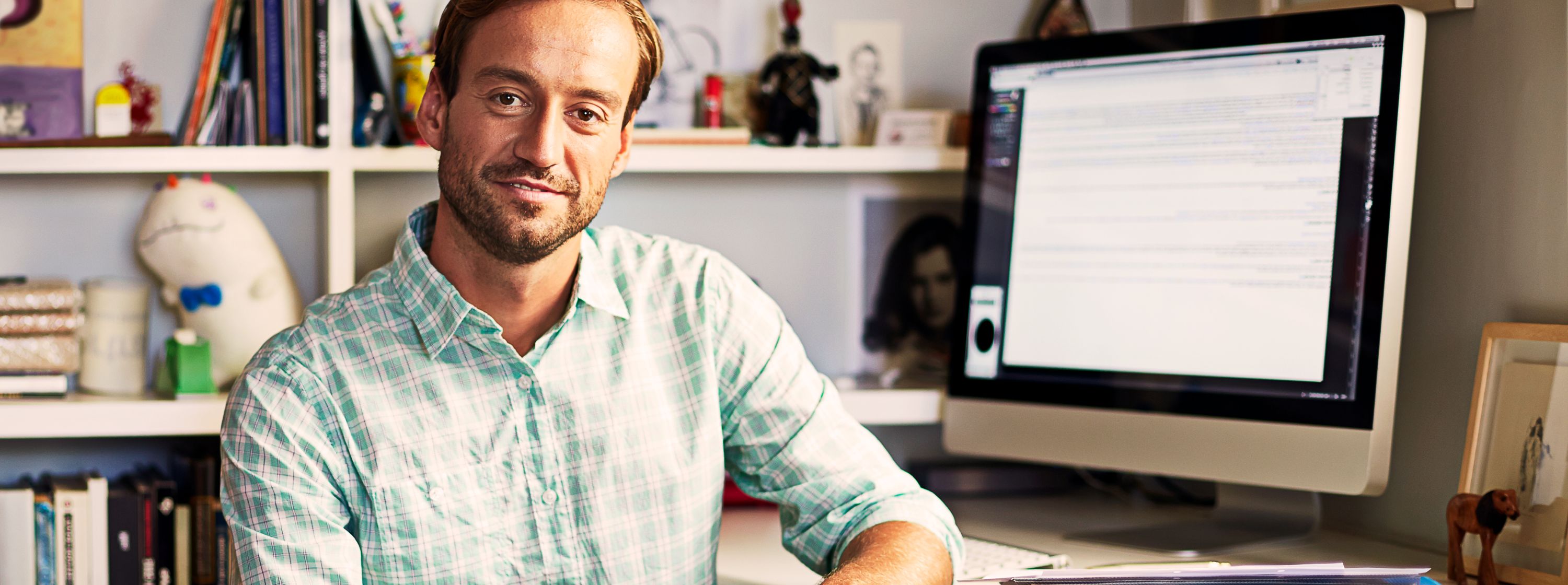 Close up of male employee smiling, sitting at his home office desk