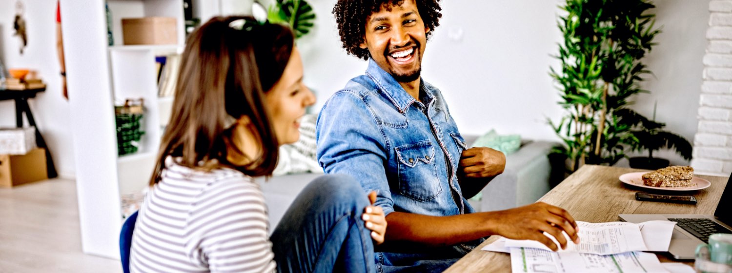 Happy married couple laughing while organizing bills at home