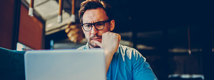 Middle-aged man looking at laptop with concerned look