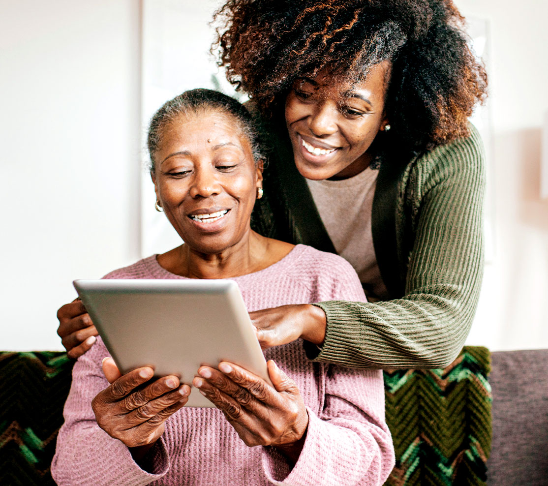 A women showing her mother how to work on her finances using a tablet